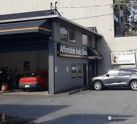 Shop exterior with open bay and vehicles parked outside