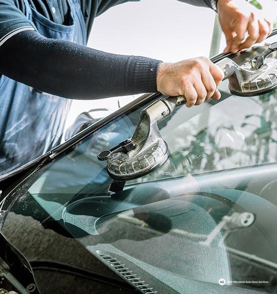 Technician using suction cups to handle a windshield on a vehicle