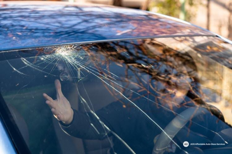 Cracked windshield with a rock chip and spreading cracks