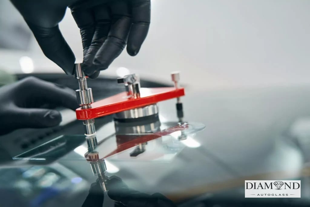 Windshield repair bridge tool clamped to glass during a chip repair