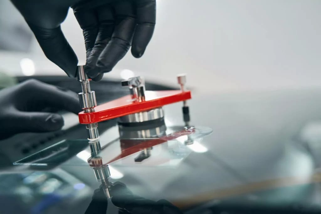 Windshield repair bridge tool clamped to glass during a chip repair