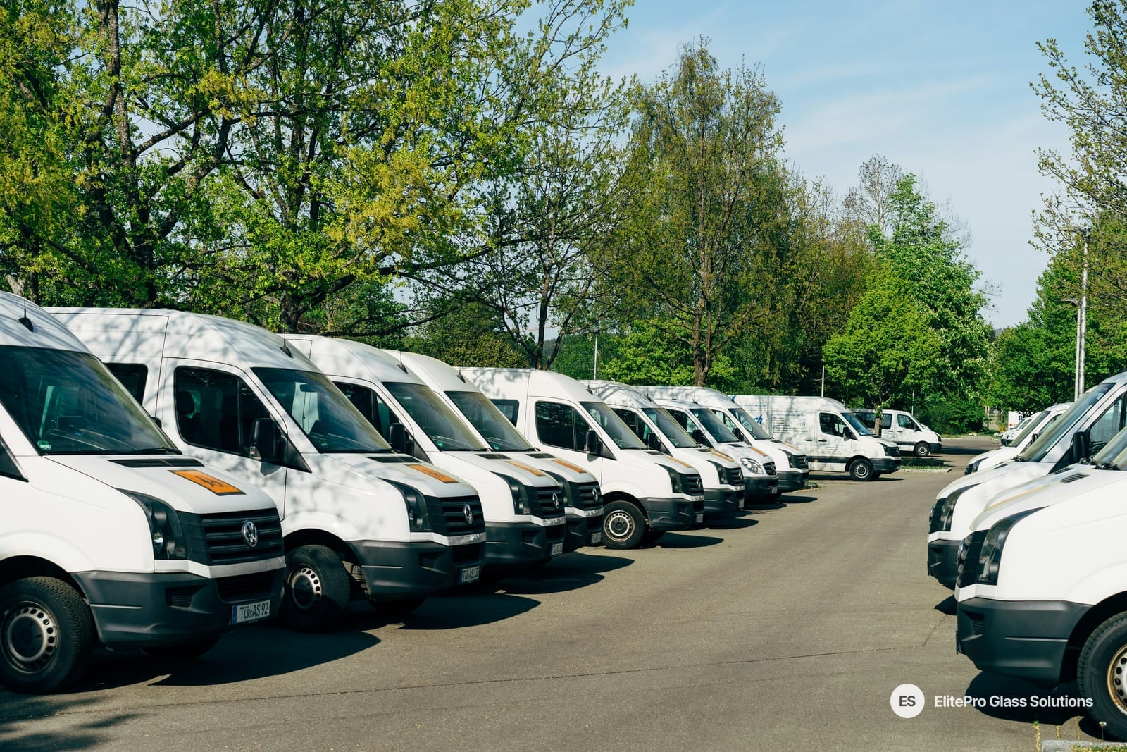 Row of white service vans parked side by side in a lot