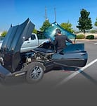 Vehicle with hood open being worked on outdoors during a glass replacement